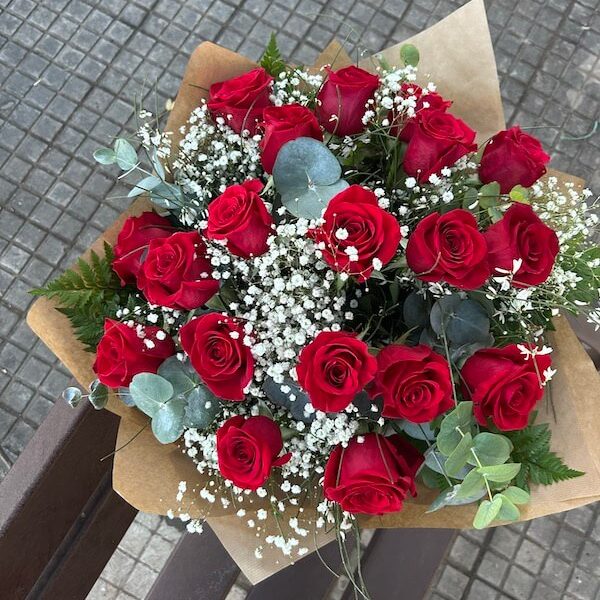 ramo de dieciocho rosas naturales con verdes decorativos que realzan la belleza del trabajo floral