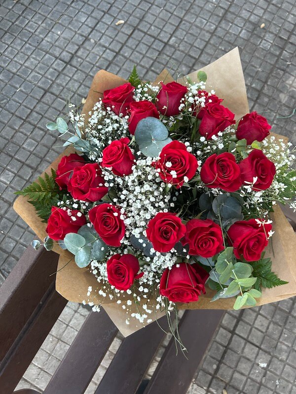 ramo de dieciocho rosas naturales con verdes decorativos que realzan la belleza del trabajo floral